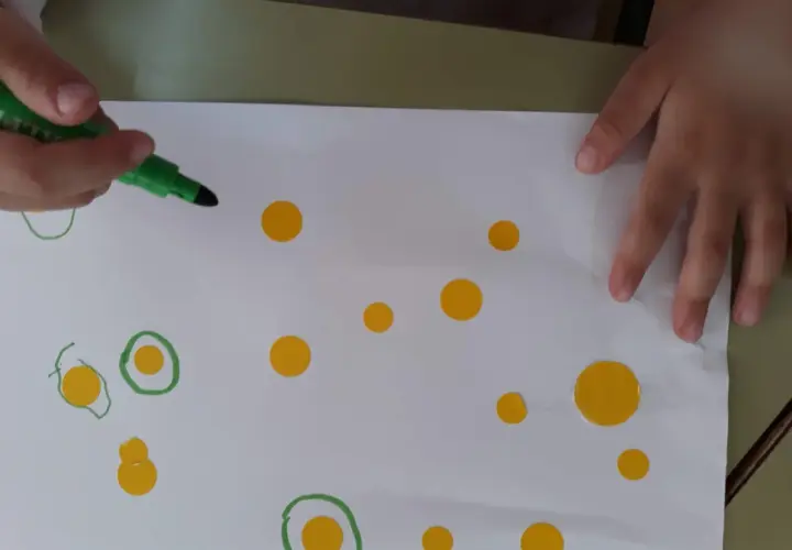 Manos de niño creando círculos y puntos, inspirándose en las kandinsky obras para niños.