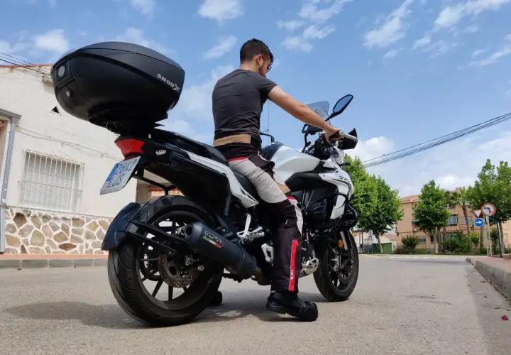 Hombre sentado en una Benelli TRK 502, mostrando la altura del asiento. La moto tiene un baúl SH59X.