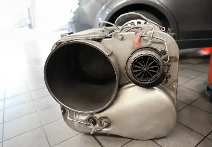 Element układu wydechowego, prawdopodobnie po usuwaniu filtra DPF. Widać dużą rurę i turbinkę.