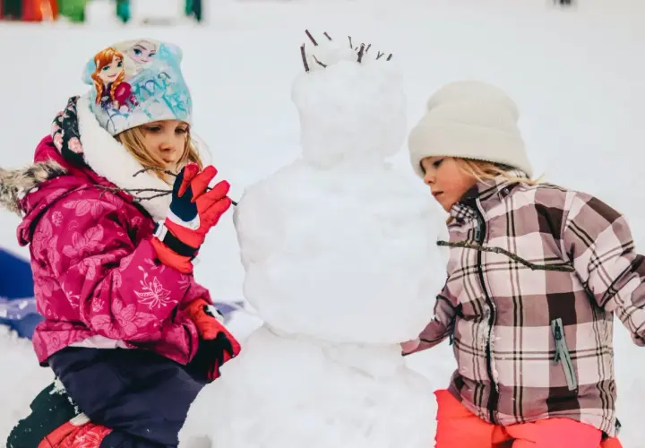 Bambini creano un pupazzo di neve in montagna, un vero natale in montagna con bambini che si divertono nella neve.
