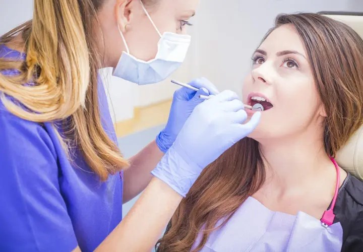 Dentystka bada jamę ustną pacjentki, szukając ewentualnych zmian.