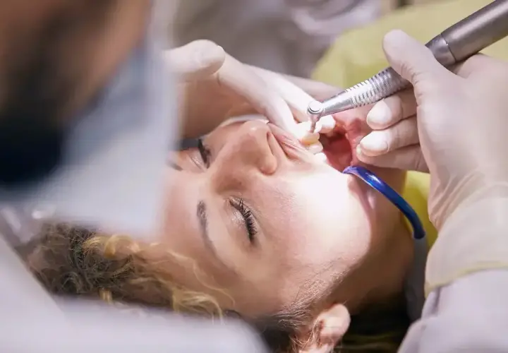 Pacjentka u dentysty, trwa zabieg. Czy leczenie kanałowe jest na NFZ? Warto sprawdzić, bo czasem można zaoszczędzić.