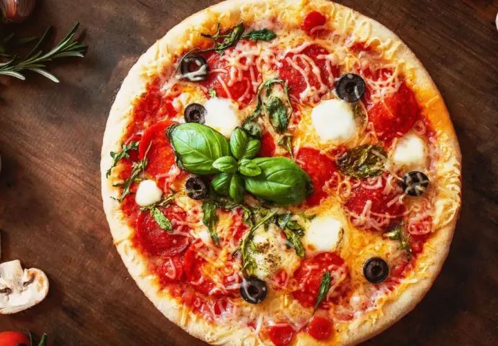 Leckere Pizza mit Salami, Mozzarella und Oliven auf einem Holzbrett. Ein schneller Pizzateig ohne Hefe macht sie im Handumdrehen fertig.