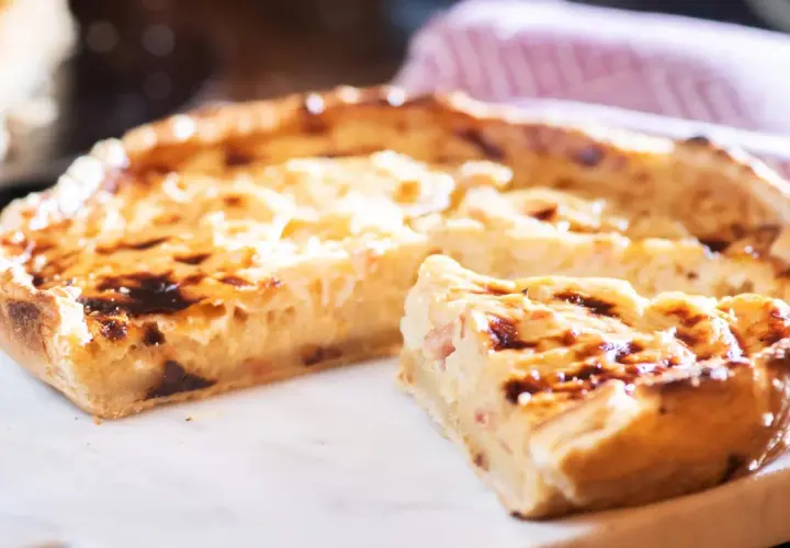 Ein köstliches Quiche Rezept, goldbraun gebacken, mit einem Stück zum Probieren.