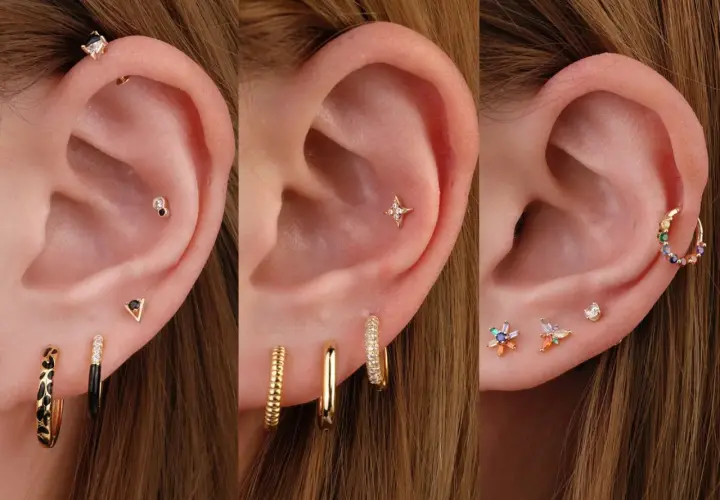 Ucho z kilkoma kolczykami, w tym błyszczącym helix piercingiem, gwiazdką i kolorowymi kamieniami.