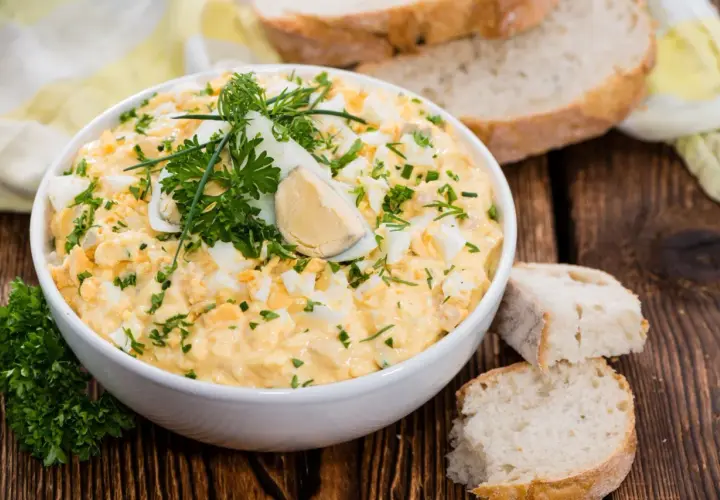 Pyszna pasta z jajek, udekorowana natką pietruszki i jajkiem na twardo, podana z chlebem.