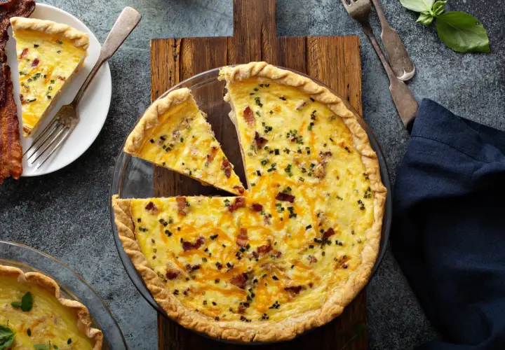 Une quiche au bacon et fromage, parfaite pour une recette quiche facile. Une part est déjà servie avec du bacon croustillant.