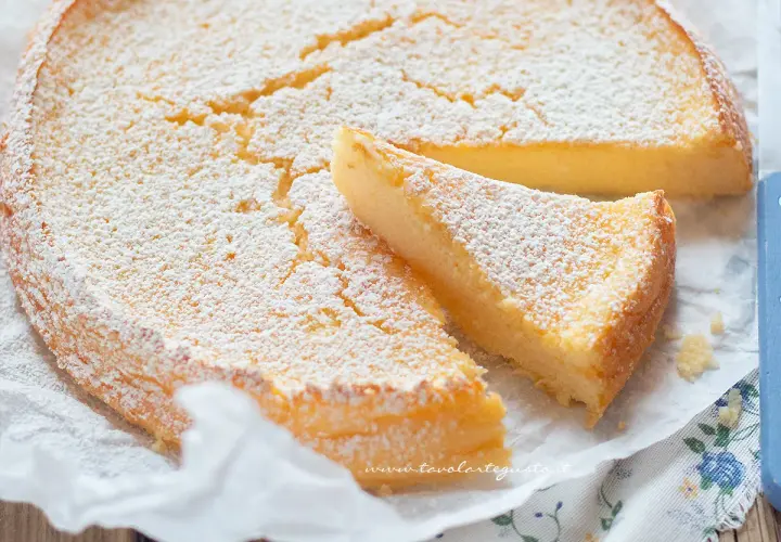 Deliziosa torta ricotta e limone, soffice e spolverata di zucchero a velo, con una fetta tagliata.