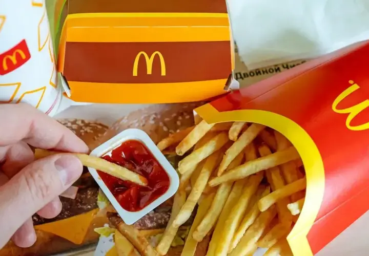 Ręka macza frytkę w ketchupie. Obok czerwone pudełko z frytkami i brązowy box z logo McDonald's. Co jest w chicken box?