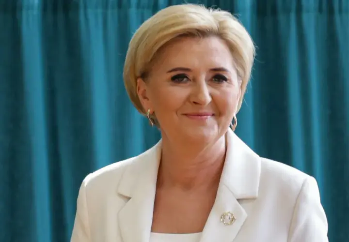 Uśmiechnięta kobieta w białej marynarce, z blond włosami i złotymi kolczykami. Czy żona prezydenta może pracować? Tak, jak najbardziej!