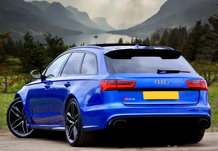 Niebieskie Audi RS6 z Niemiec, gotowe do rejestracji. Piękne góry i jezioro w tle.
