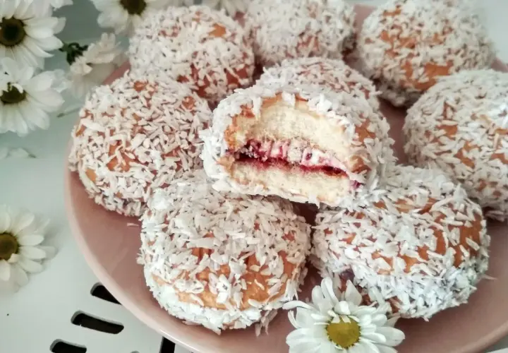 Pyszne ciastka biszkoptowe z nadzieniem owocowym i wiórkami kokosowymi, wyglądają jak małe śnieżne kuleczki.