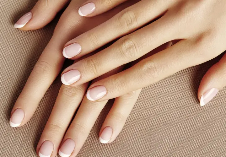 Dłonie z perfekcyjnym manicurem french kombinowany. Delikatny róż i biel podkreślają elegancję.