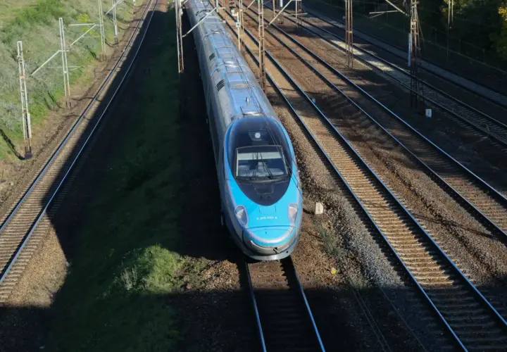 Błękitny pociąg Pendolino EIP mknie po torach.