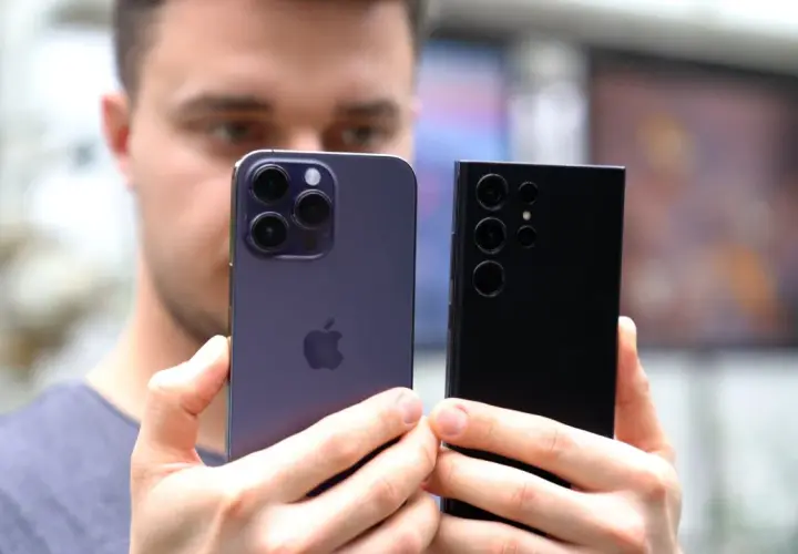 Porównanie aparatów iPhone'a i Samsunga. Który telefon ma najlepszy aparat? Dwa flagowe smartfony w dłoniach mężczyzny.