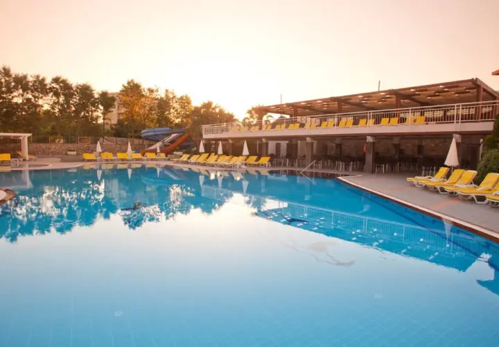 Basen w club mermaid village, z leżakami i zjeżdżalniami, w blasku zachodzącego słońca.