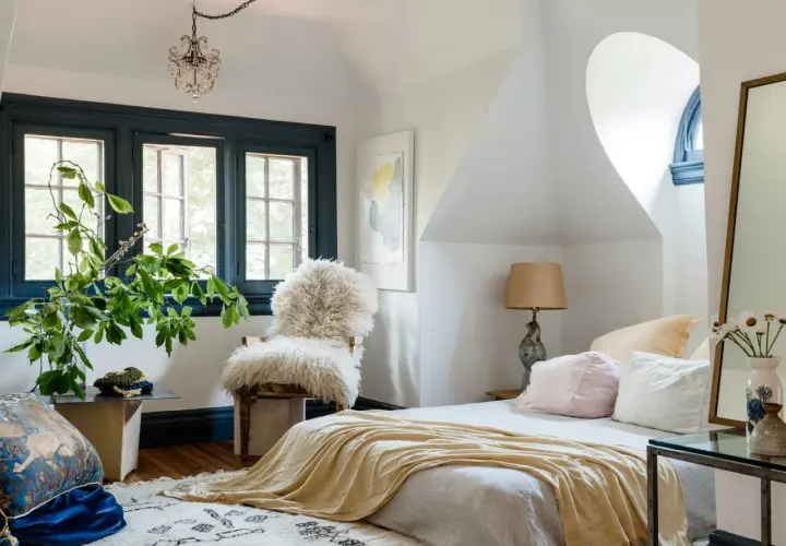 Cozy bedroom with a fluffy chair, yellow throw, and plants. Learn how to pick bedroom furniture for a stylish, inviting space.