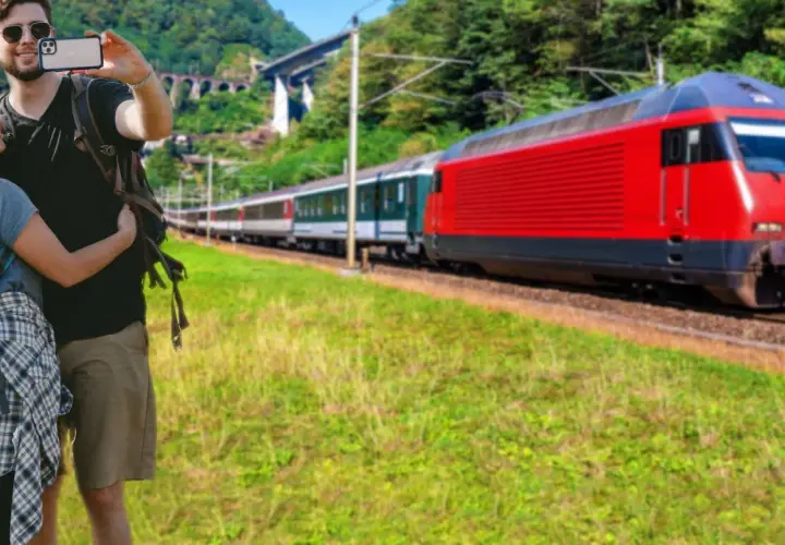 Para podróżnych z plecakami, którzy robią sobie selfie, na tle czerwonego pociągu jadącego w kierunku Krakowa Głównego i Bochni.