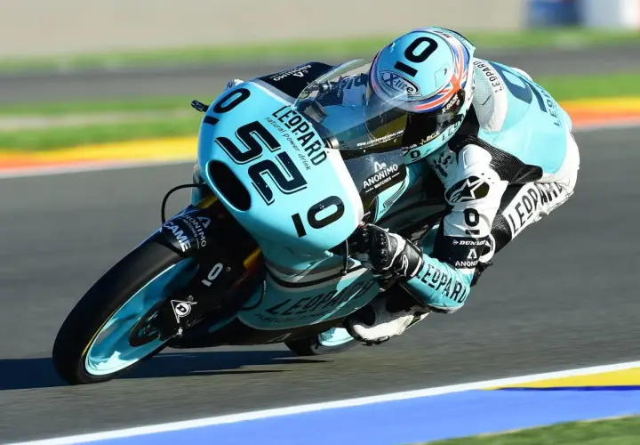 Danny Kent inclinado en su moto azul y negra, número 52, compitiendo en una carrera.