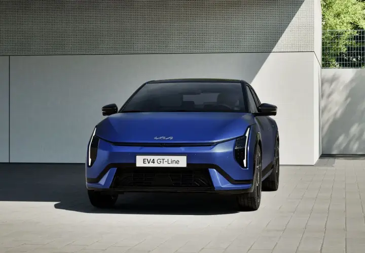 Niebieski Kia EV4 GT-Line, elektryczny sedan, prezentuje się nowocześnie przed budynkiem.