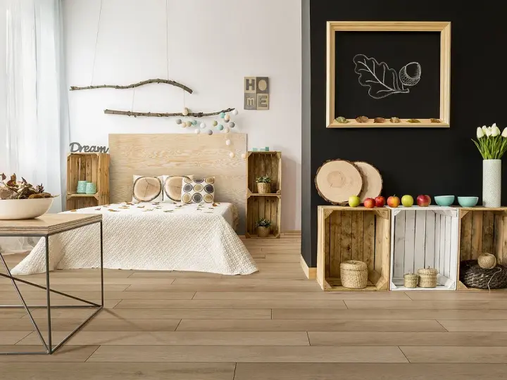 Jak pogodzić salon z sypialnią? Drewniane skrzynki, łóżko z drewnianym zagłówkiem i dekoracje w stylu rustykalnym tworzą przytulną przestrzeń.