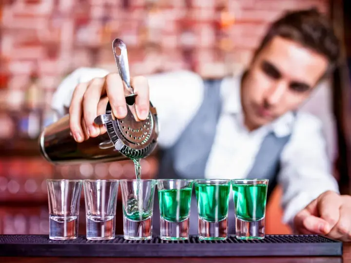 Barman nalewa zielony shot. Chcesz wiedzieć, jak zostać barmanem? To pierwszy krok do mistrzostwa!