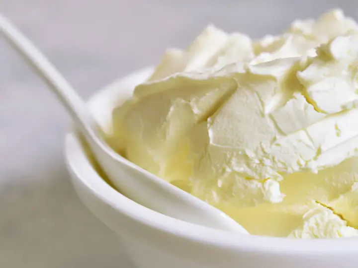 Kremowa masa w białej miseczce z łyżką. Idealna do deserów, gdy szukasz, czym zastąpić mascarpone.