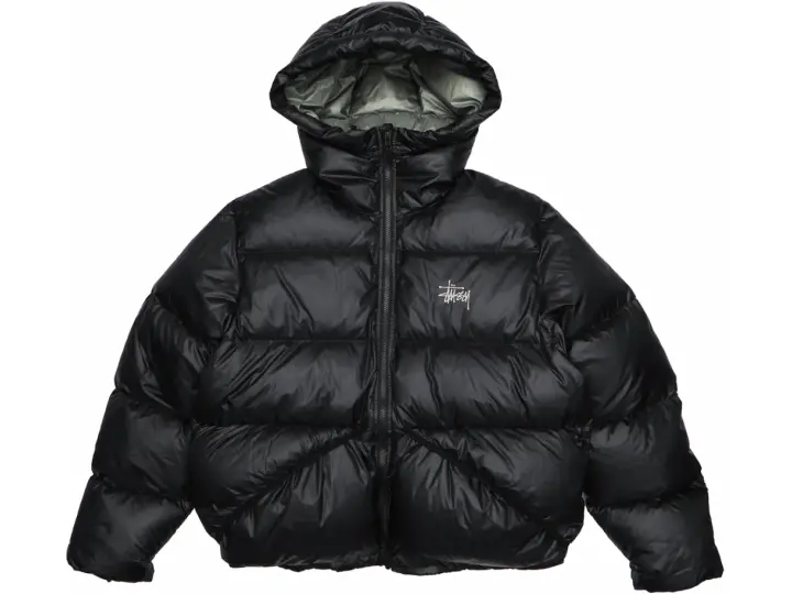 Piumino nero Stussy con cappuccio e logo bianco sul petto. Perfetto per affrontare il freddo con stile.