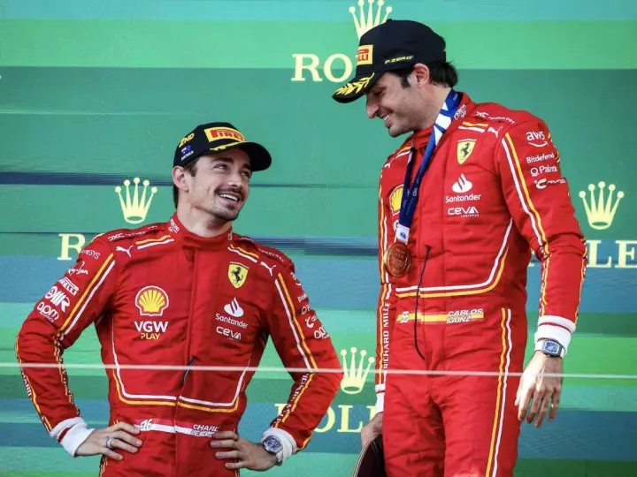 Carlos Sainz, con su altura destacada, sonríe en el podio junto a su compañero.