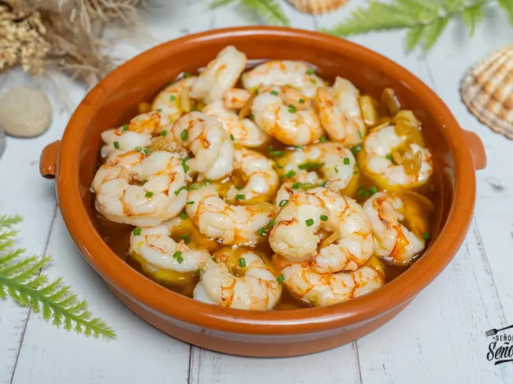Gambas al ajillo burbujeantes en cazuela de barro, con perejil picado y un toque de aceite de oliva. ¡Un clásico irresistible!