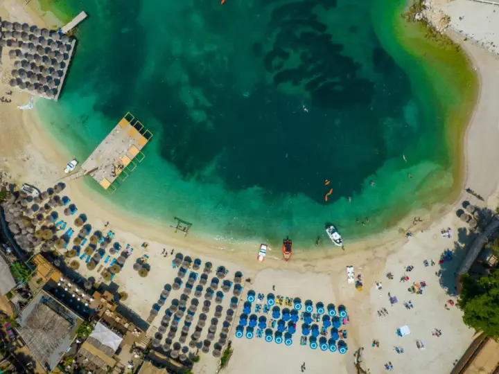Albania, lipiec: słoneczna pogoda na plaży z turkusową wodą, leżakami i parasolami. Idealne warunki do wypoczynku.