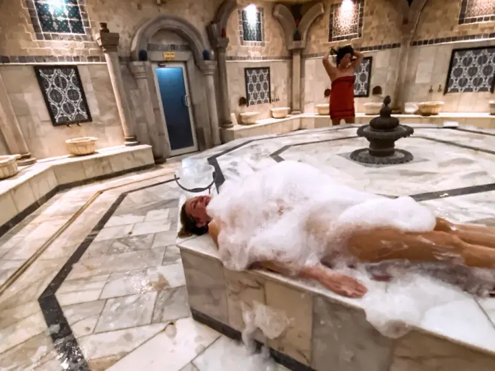 Kobieta w pianie w łaźni hammam. To tradycyjne tureckie łaźnie parowe, miejsce relaksu i oczyszczenia.