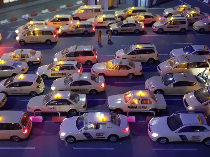 Modellautos von Taxis stehen im Stau. Die Lichter leuchten, als ob sie Nachtzuschlag berechnen würden.