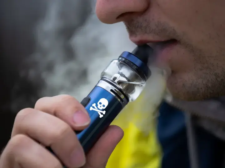 Persona vapeando un dispositivo con calavera, advirtiendo sobre los vapear efectos secundarios.