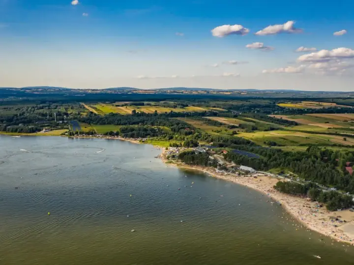 Letnie słońce nad **Jeziorem Chańcza**. Tłumy plażowiczów, zielone lasy i pola tworzą malowniczy krajobraz.