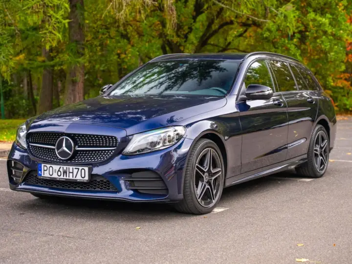 Granatowy Mercedes C klasa W205 kombi zaparkowany na tle jesiennego lasu.