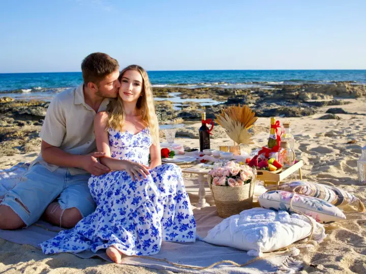 Romantyczny piknik na plaży na Cyprze. Para cieszy się chwilą, a na stole czekają przysmaki. Idealne na wycieczki fakultatywne.