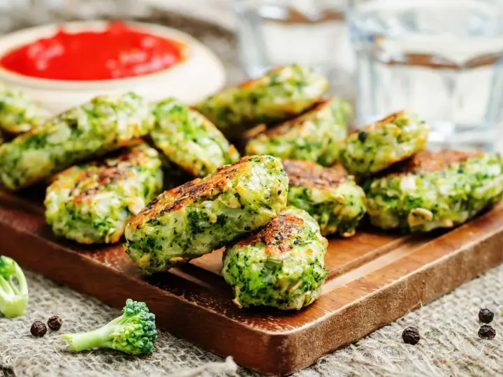 Deliciosas bolitas de brócoli, perfectas para tus recetas con brócoli. Servidas con salsa roja y un toque de pimienta.