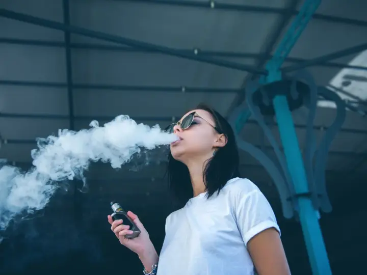 Joven exhala humo de un vaper, una práctica que demuestra que el vaper es malo para la salud.