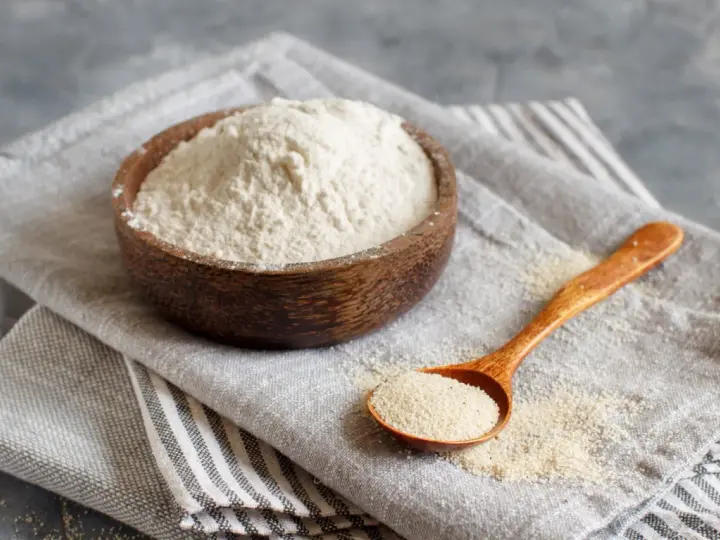 Mąka gryczana w drewnianej misce i na łyżce. Czy mąka gryczana ma gluten? Nie, jest bezglutenowa.