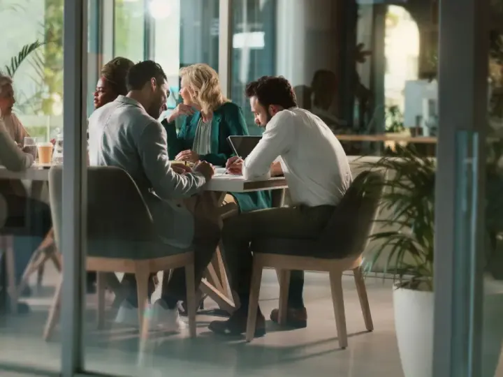 Des employés discutent autour d'une table, mais chacun semble travailler dans son coin, comme s'ils étaient en train de travailler en silo.