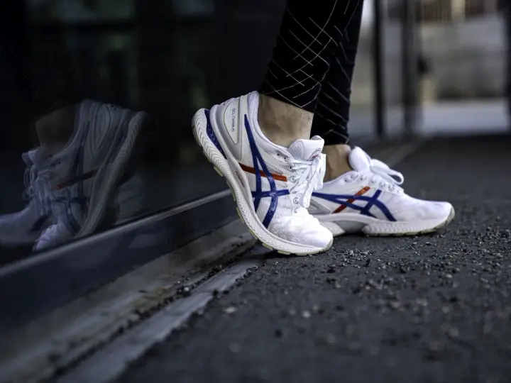 Vita Asics-skor med blå och röda detaljer, perfekt för löpning. Kolla in vår asics storleksguide för rätt passform.