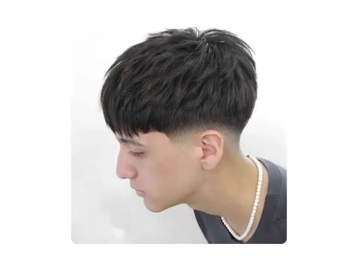 Joven con corte de pelo moderno, un low fade hombre con la parte superior texturizada y flequillo recto.
