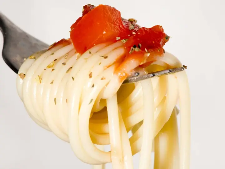 Eine Gabel mit Spaghetti, belegt mit Tomaten und Kräutern. Ein Vorgeschmack auf die besten italienischen Pasta Rezepte.