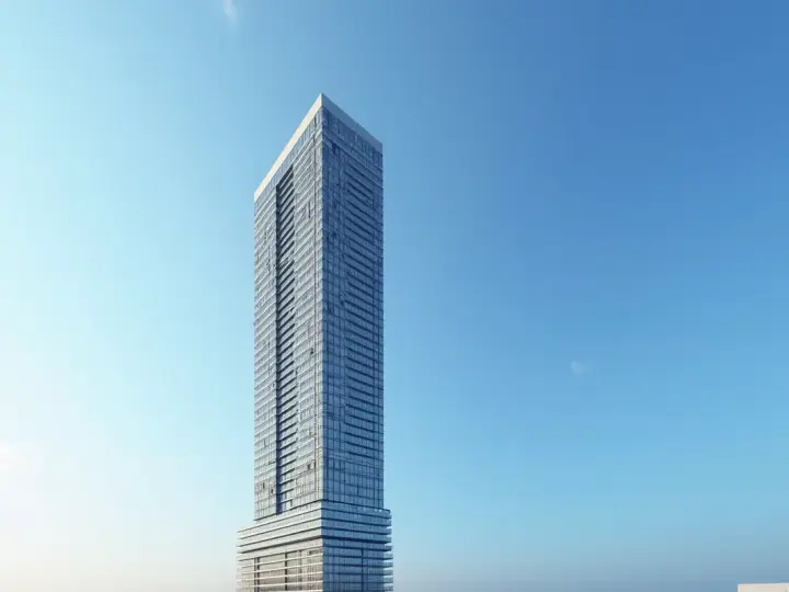 Nowoczesny wieżowiec z przeszkloną fasadą na tle błękitnego nieba. Trudno jednoznacznie określić, ile pięter ma ten skytower, ale z pewnością jest ich wiele.