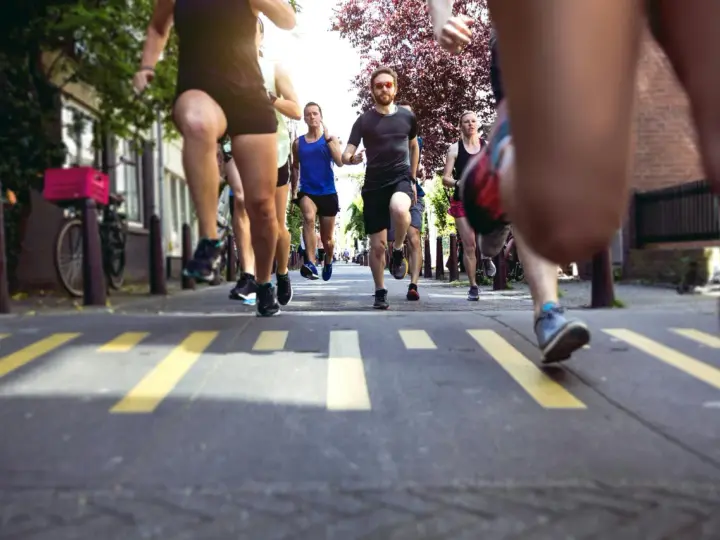 En grupp löpare kämpar sig fram på asfalten, redo att springa halvmaraton. Gula linjer på vägen markerar banan.