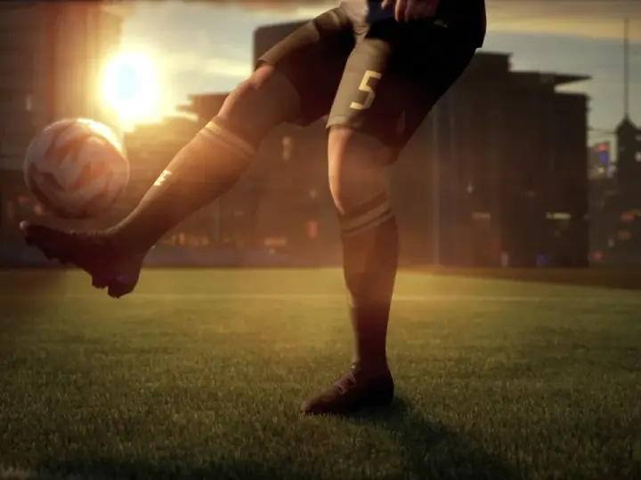 Jugador de fútbol con el número 5 en su pantalón corto, pateando un balón en un campo al atardecer. El sol brilla intensamente detrás de los edificios de la ciudad. ufl pc.