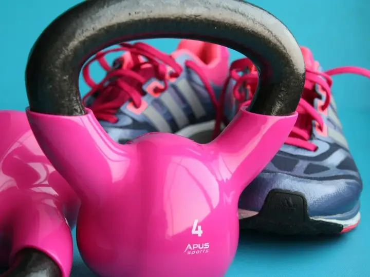 Różowe kettlebelle i buty sportowe marki Adidas gotowe do treningu.