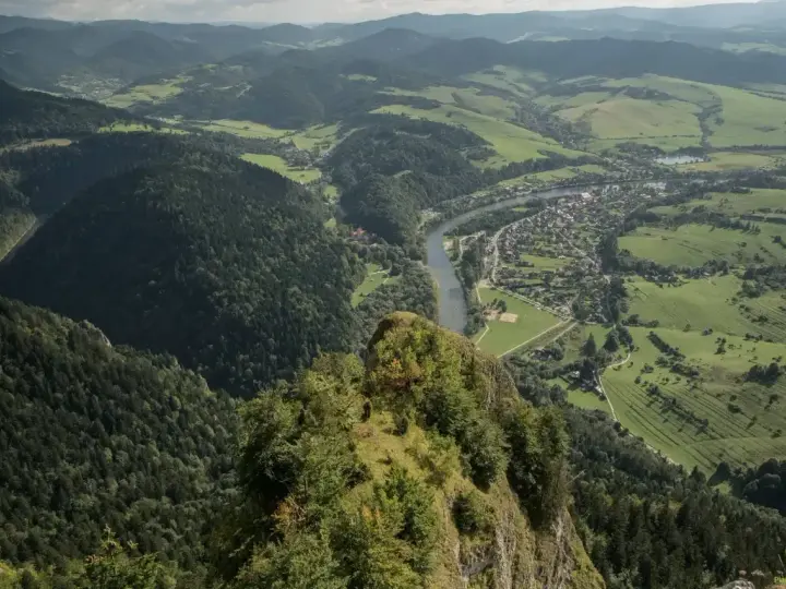 Widok z góry na malowniczą dolinę Dunajca, lasy i zabudowania. W oddali widać fragment szlaku Trzy Korony.