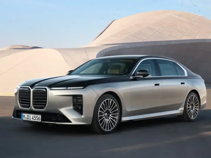 Elegancki BMW 740d w dwukolorowym malowaniu, zaparkowany przed nowoczesnym budynkiem.